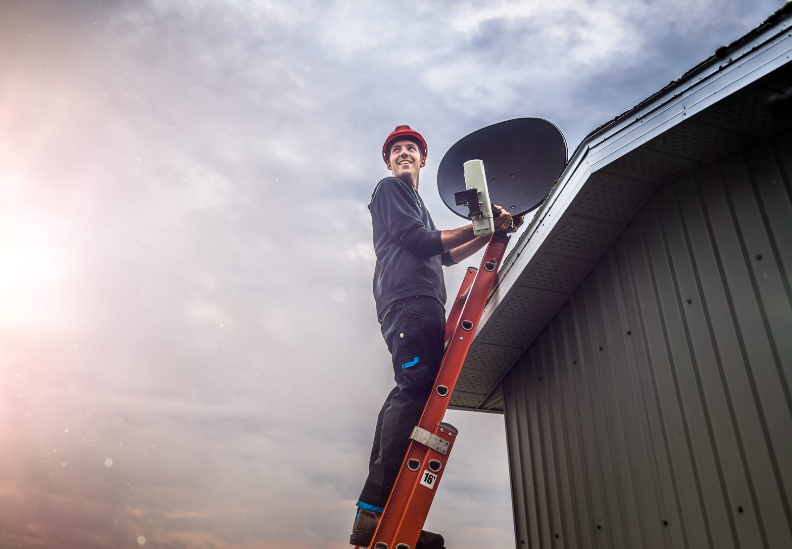 Accredited DSTV technician on a ladder installing a satellite dish at a Arcadia home